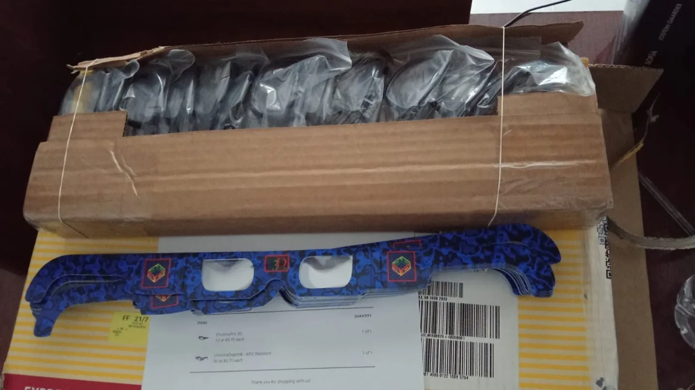 A box of ChromaDepth 3D glasses, with one hand-painted pair on top