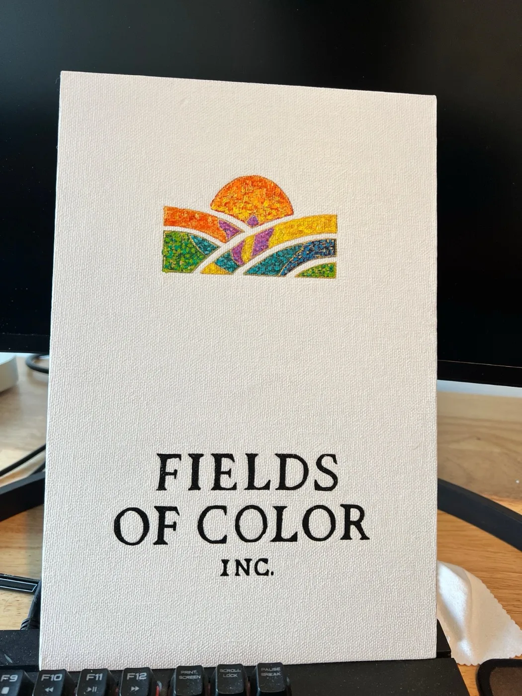 The hand-painted Fields of Color logo on canvas board